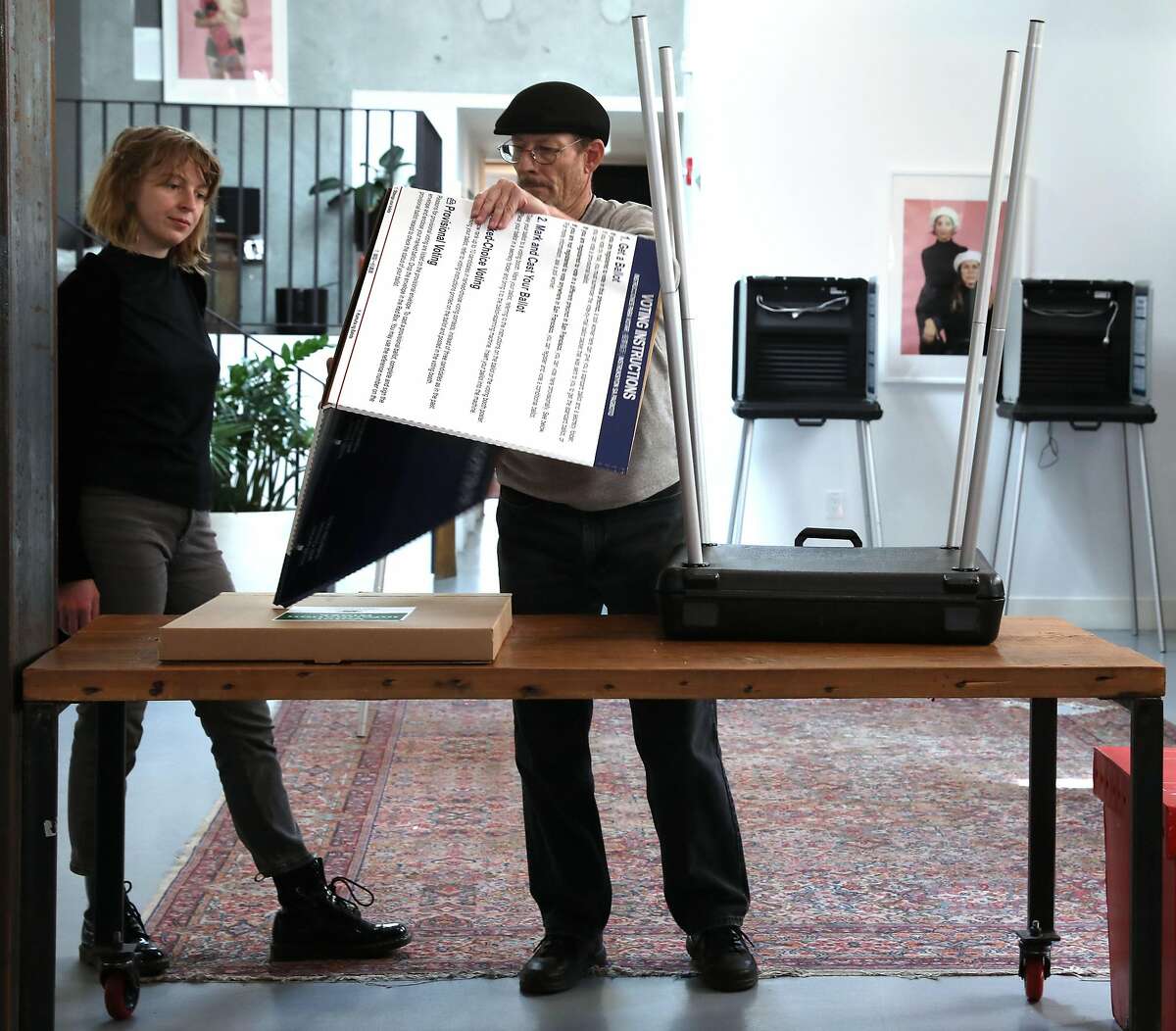 The Laundry manager Taylor Ovca (left) works with roving district support team supervisor Bill Delaney (middle) as he sets up a polling space at the coffee shop/gallery on Monday, March 2, 2020, in San Francisco, Calif.