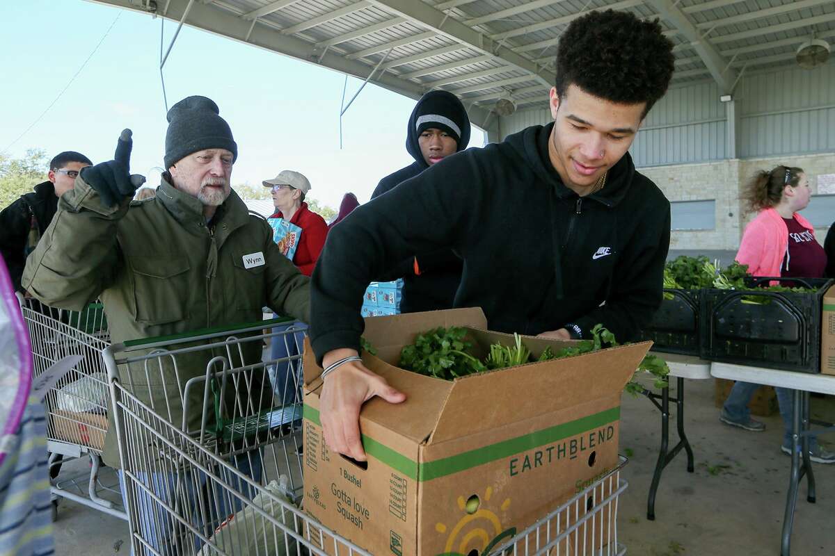 Kade Moss, 17, with Clemens High School’s culinary arts program, loads a box of food into a basket at the mobile food pantry funded by Bracken United Methodist Church at Pickrell Park in Schertz on Wednesday.