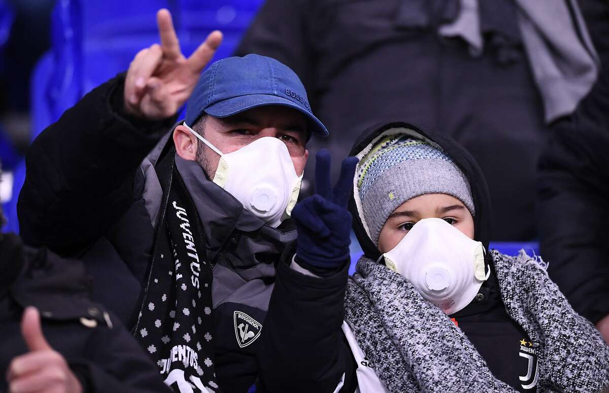 TOPSHOT - Juventus supporters wear protective face masks as a safety measure against the COVID-19 novel coronavirus at the Parc Olympique Lyonnais stadium in Decines-Charpieu, central-eastern France, on February 26, 2020, ahead of the UEFA Champions League round of 16 first-leg football match between Lyon and Juventus. (Photo by FRANCK FIFE / AFP) (Photo by FRANCK FIFE/AFP via Getty Images)