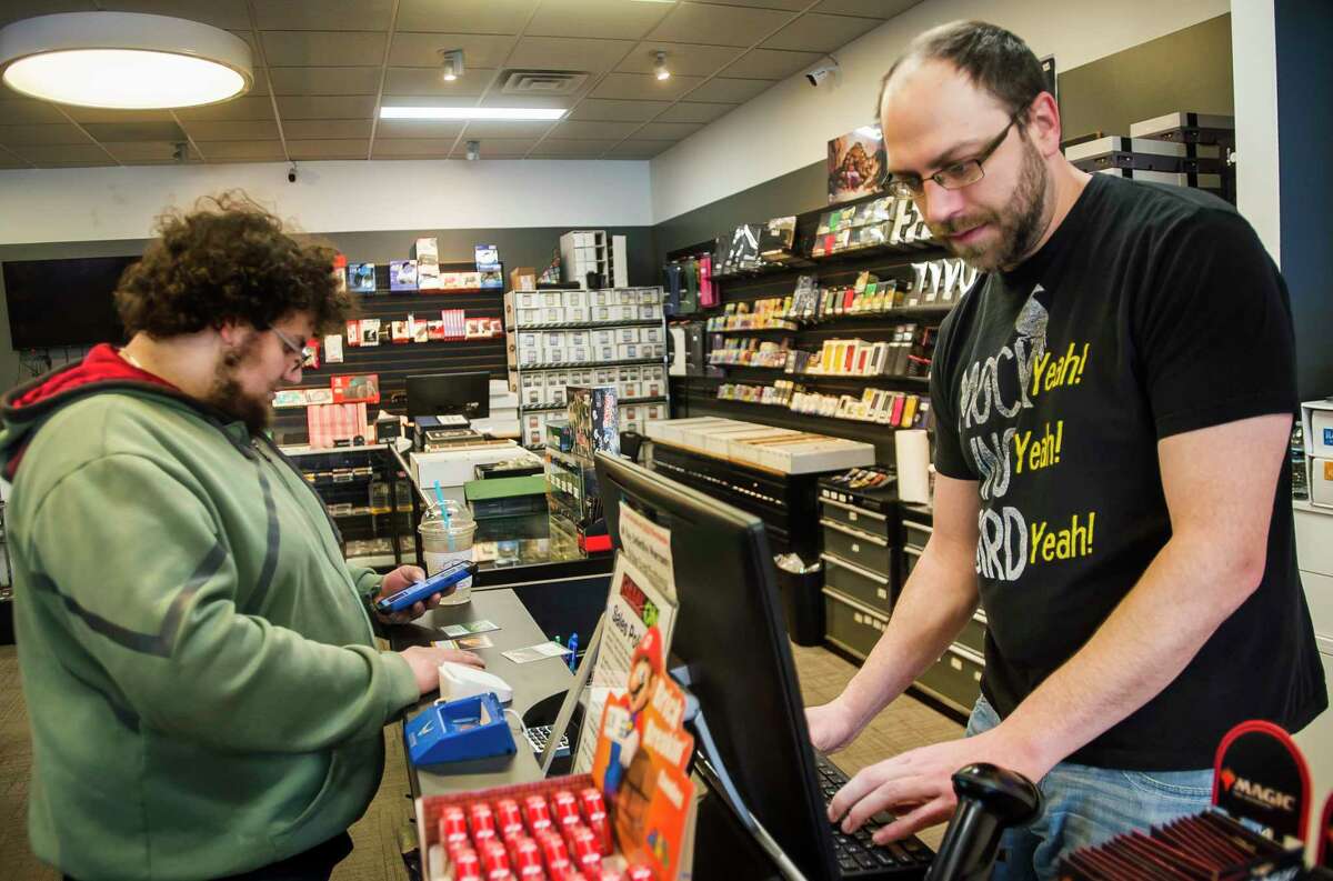 Tyler Smith, left, purchases playing cards from Game On manager Joe Dempsey, right, before playing a game of Magic: The Gathering with friends Monday, March 2, 2020 at the store, which recently moved to 814 S. Saginaw Road. (Katy Kildee/kkildee@mdn.net)