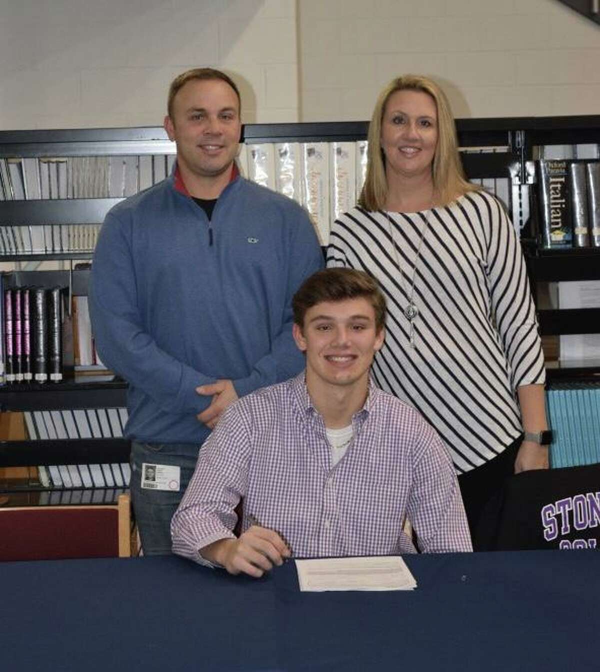 Foran High's Andrew Janik, with his father Jeff and mother Lauren, signs his letter of intent to play football at Stonehill College.