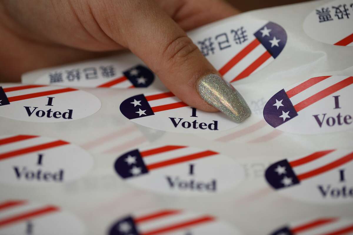 Poll worker Rachele Huennekens holds “I Voted” stickers for voters at the Marsha J. Corprew Memorial Lakeside Park Garden Center in Oakland, Calif., on Tuesday, March 3, 2020. Super Tuesday brings a look at California’s fairly new rules allowing people to change party registration on Election Day.