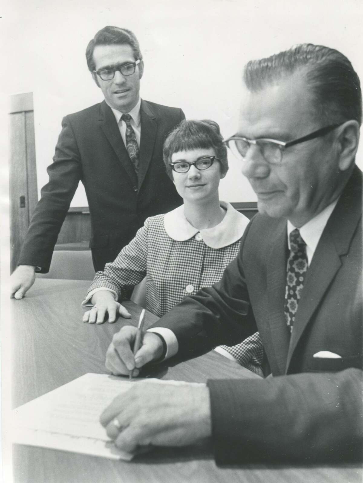 Julius Blasy, Mayor of Midland, signs a document. Others are unknown.