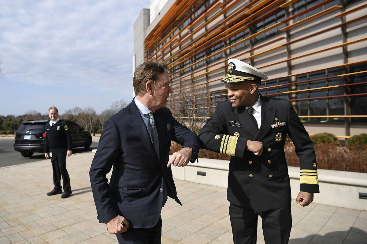 U.S. Surgeon General Vice Admiral Jerome M. Adams, right, bumps elbows with Connecticut Gov. Ned Lamont as they meet for a visit at the Connecticut State Public Health Laboratory, Monday, March 2, 2020, in Rocky Hill, Conn. The Surgeon General is encouraging people to bump elbows rather than shaking hands or fist bumps to help prevent the spread of COVID-19. (AP Photo/Jessica Hill)