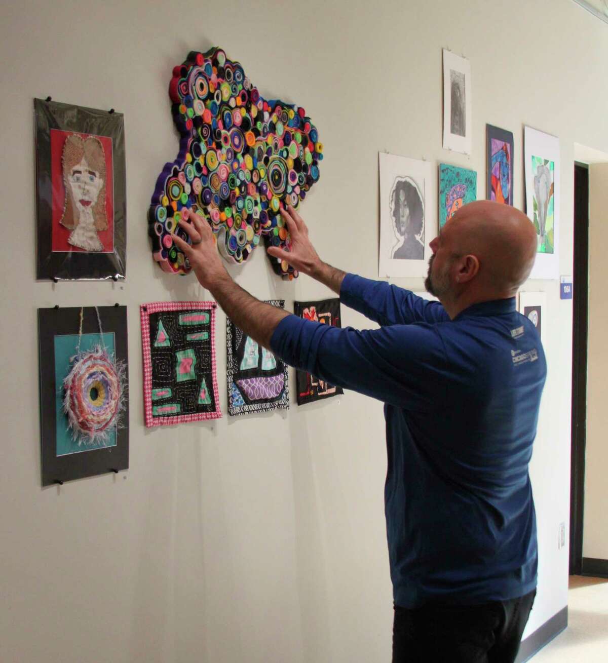 WSCC associate professor of arts Eden Foley hangs one of the 111 pieces of art that are on display at the college's Regional High School Art Show. (Ken Grabowski/News Advocate)