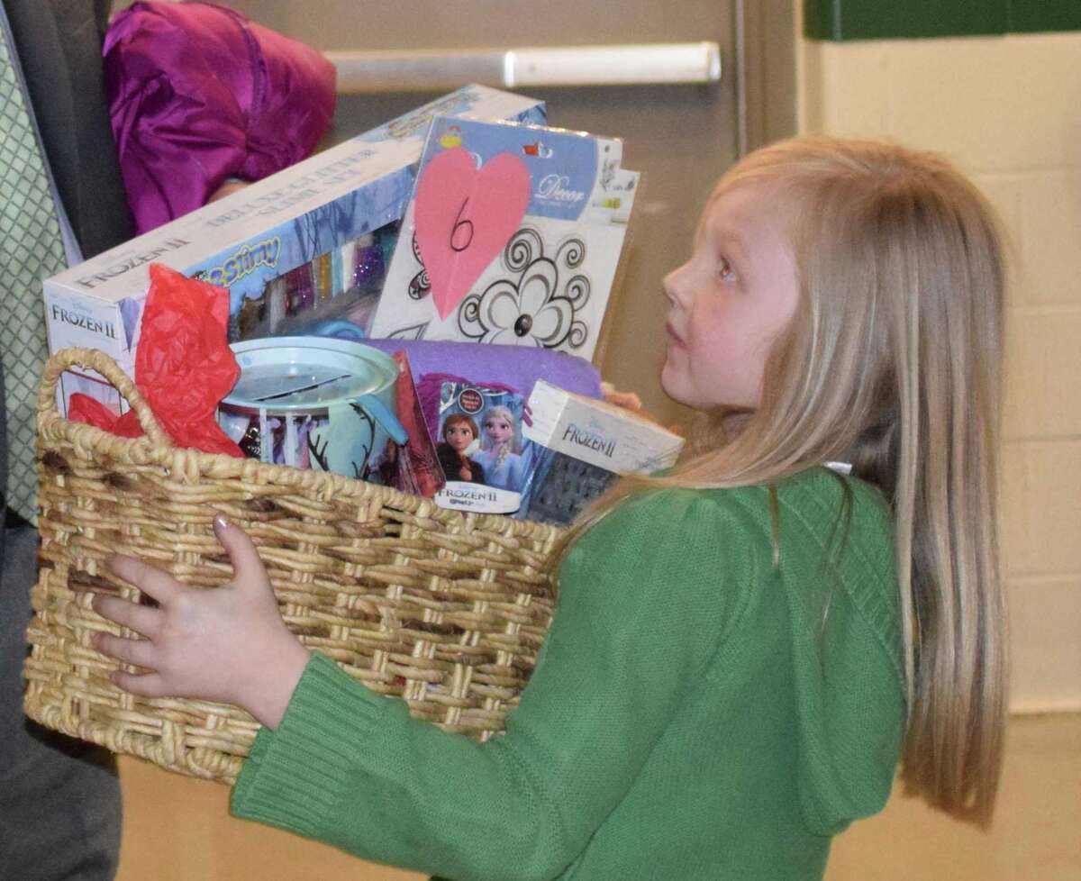 Spectrum/New Milford Girl Scout Troop 40270 hosted the annual Sweetheart Dance at New Milford High School Feb. 22, 2020.The event featured formal photos, a silent auction, dancing, refreshments and more. Above, Coeli Grasseler, 7, of Sherman looks to her father, Paul, for help in carrying her auction item to the car.