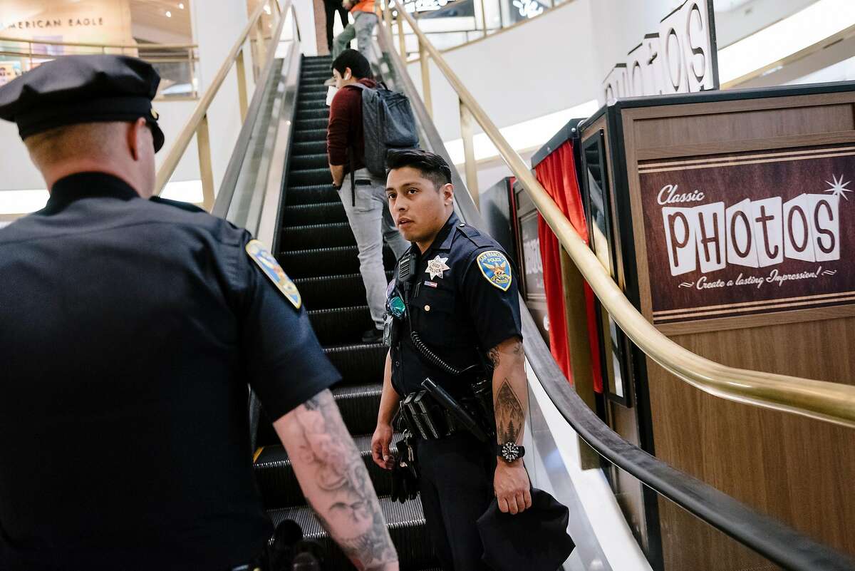 San Francisco Police Officers Nick Parkin, right, and Cory McDowell look for a person causing a disturbance in the Westfield Mall after being tipped off by a patron, in San Francisco, California, on Wednesday, March 4, 2020.