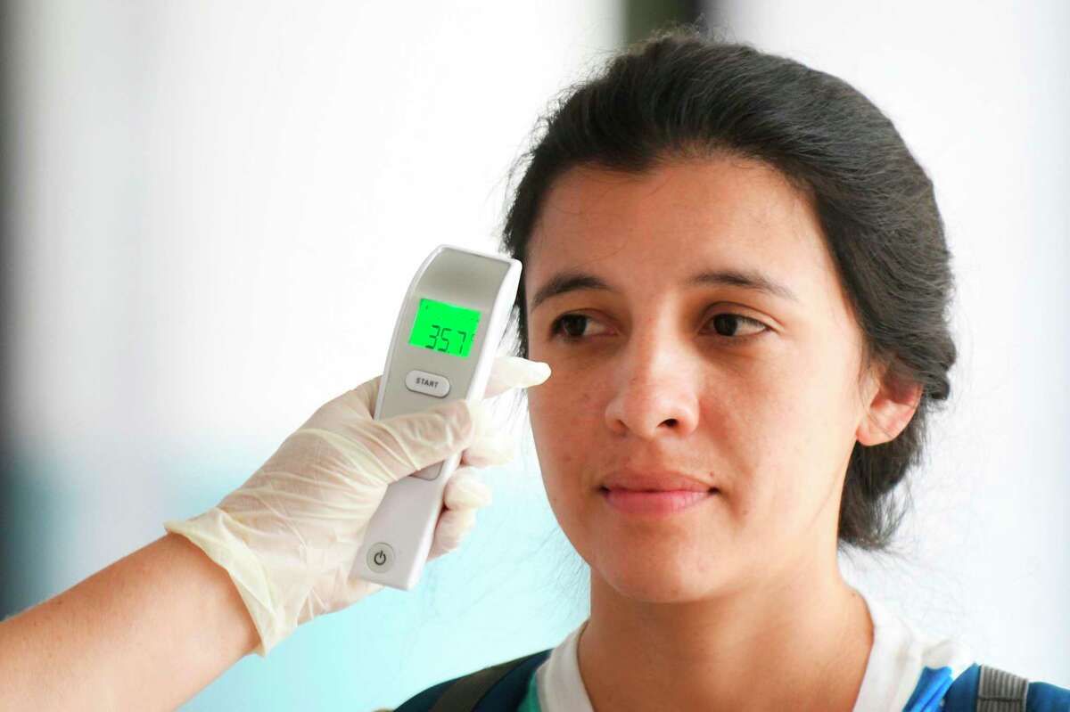 A nurse checks a passenger's body temperature as a preventive measure against the new coronavirus, COVID-19, at the Aurora International Airport, in Guatemala City, on March 4, 2020. - Guatemalan health authorities enforce controls at the airport following the rise of COVID-19 cases. (Photo by Johan ORDONEZ / AFP) (Photo by JOHAN ORDONEZ/AFP via Getty Images)