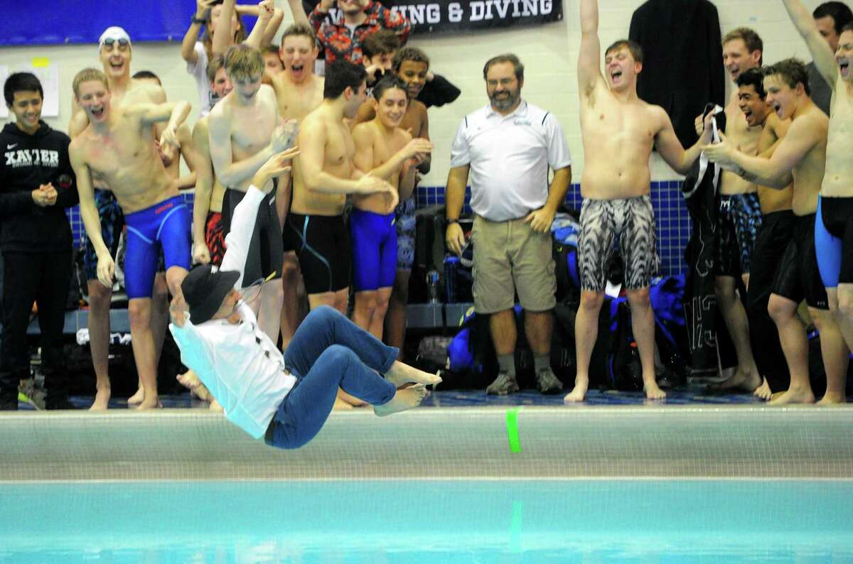Xavier coach Ronald Vaughan leaps into the pool after the school won the SCC boys swimming championship at Southern Connecticut State University in New Haven on Wednesday.