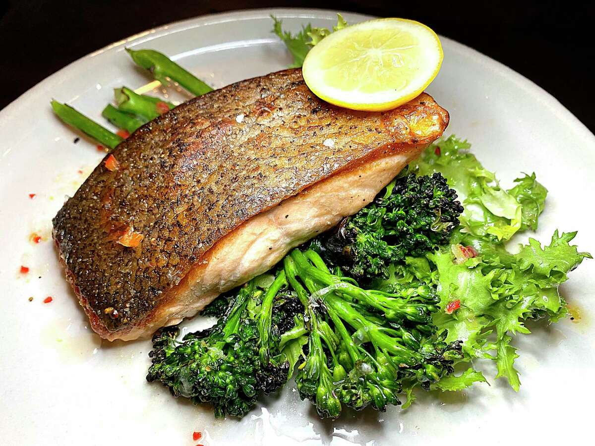 Crispy-skin salmon with preserved citrus chile paste rests on grilled broccolini at The Magpie.