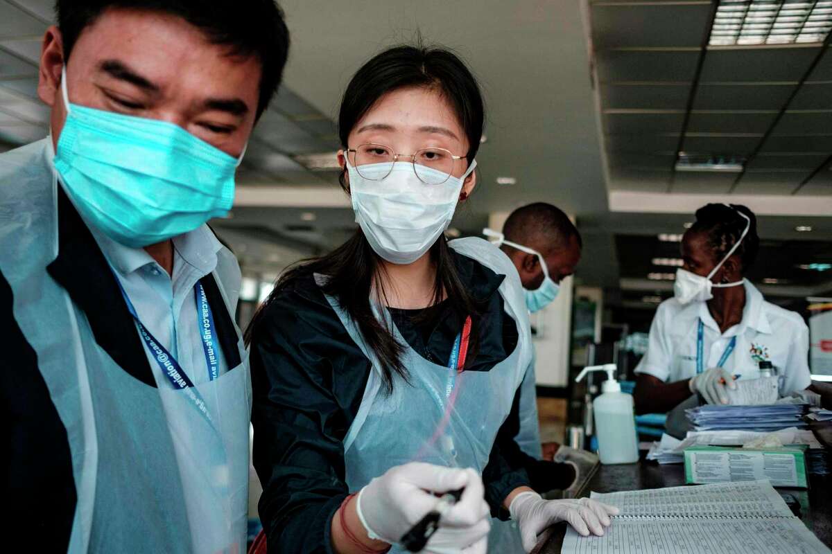 Chinese embassy officials and airport personnel prepare for passengers arriving on international flights. The response to the novel coronavirus by the Chinese and U.S. governments is a symptom for a political disregard for science.