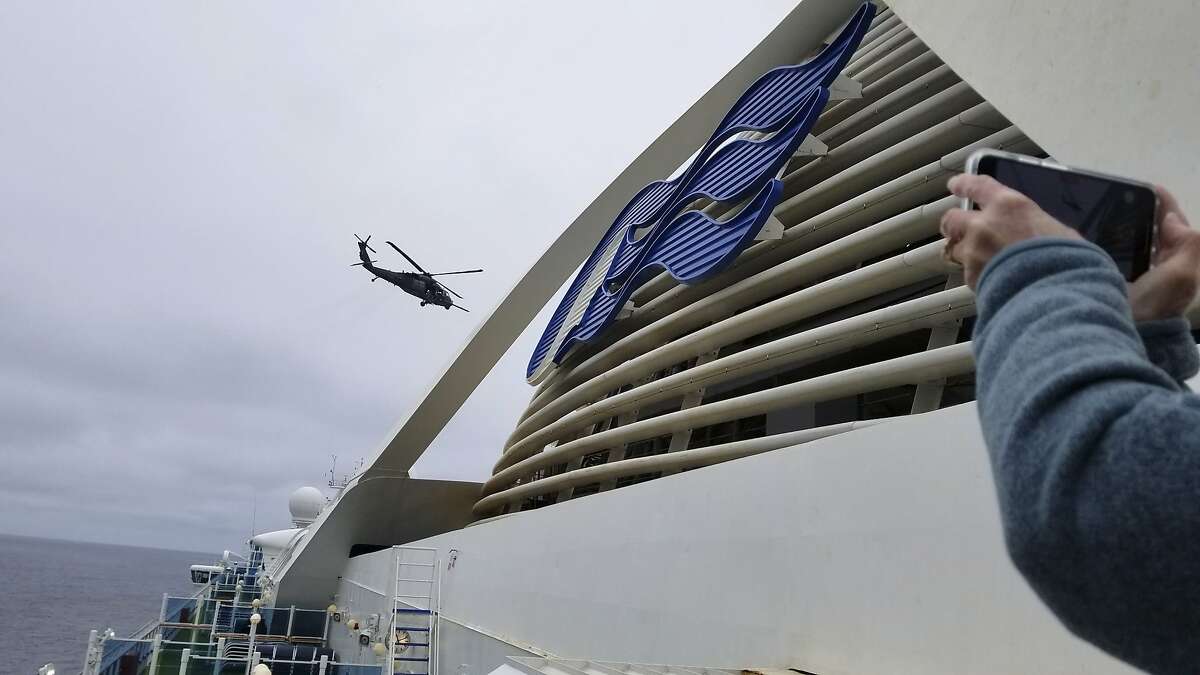 In this photo provided by Michele Smith, a California Air National Guard helicopter delivering virus testing kits hovers above the Grand Princess cruise ship Thursday, March 5, 2020, off the California coast. Scrambling to keep the coronavirus at bay, officials ordered a cruise ship with about 3,500 people aboard to hold off the California coast Thursday until passengers and crew could be tested, after a traveler from its previous voyage died and at least one other became infected. Princess Cruises says fewer than 100 of those aboard have been identified for testing. (Michele Smith via AP)