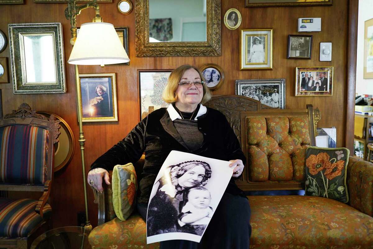 Sandy Maceyka poses at her home with a photo of Elizabeth Cady Stanton with one of her children on Thursday, March 5, 2020, in Johnstown, N.Y. Maceyka is sitting on a couch from the Cady Stanton time period. (Paul Buckowski/Times Union)
