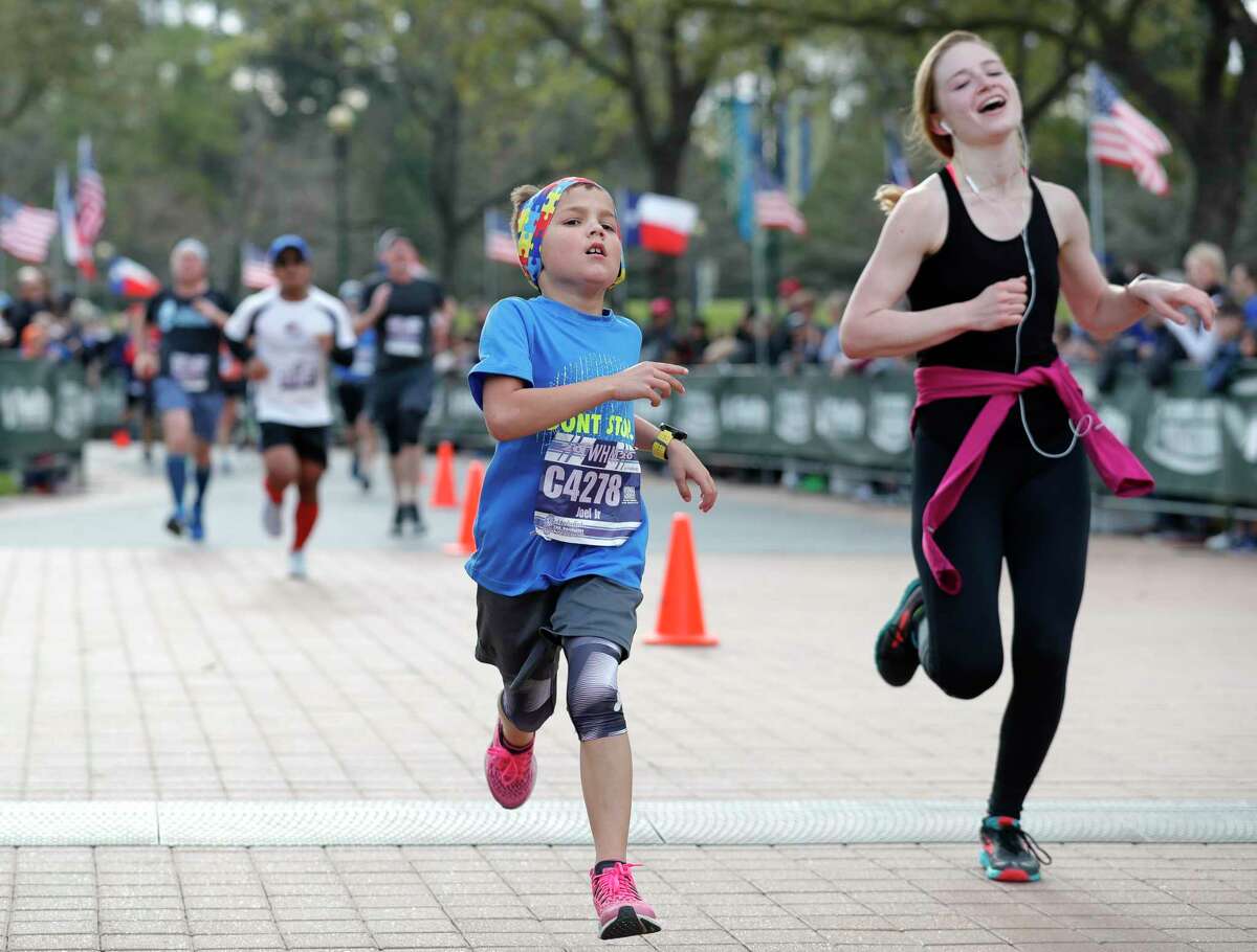 Eight-year-old Joel Redmond, Jr. crosses the finish line after completing the half marathon race during The Woodlands Marathon, Saturday, March 7, 2020, in The Woodlands.