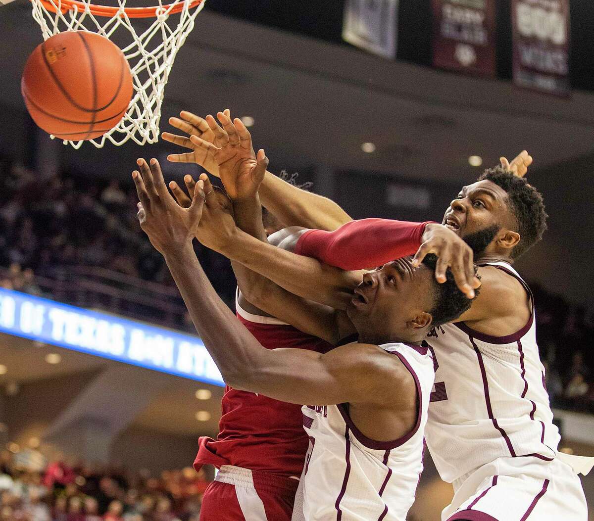 Texas A&M's Emanuel Miller, left, and Josh Nebo vie with Arkansas' Adrio Bailey for the ball on Saturday.