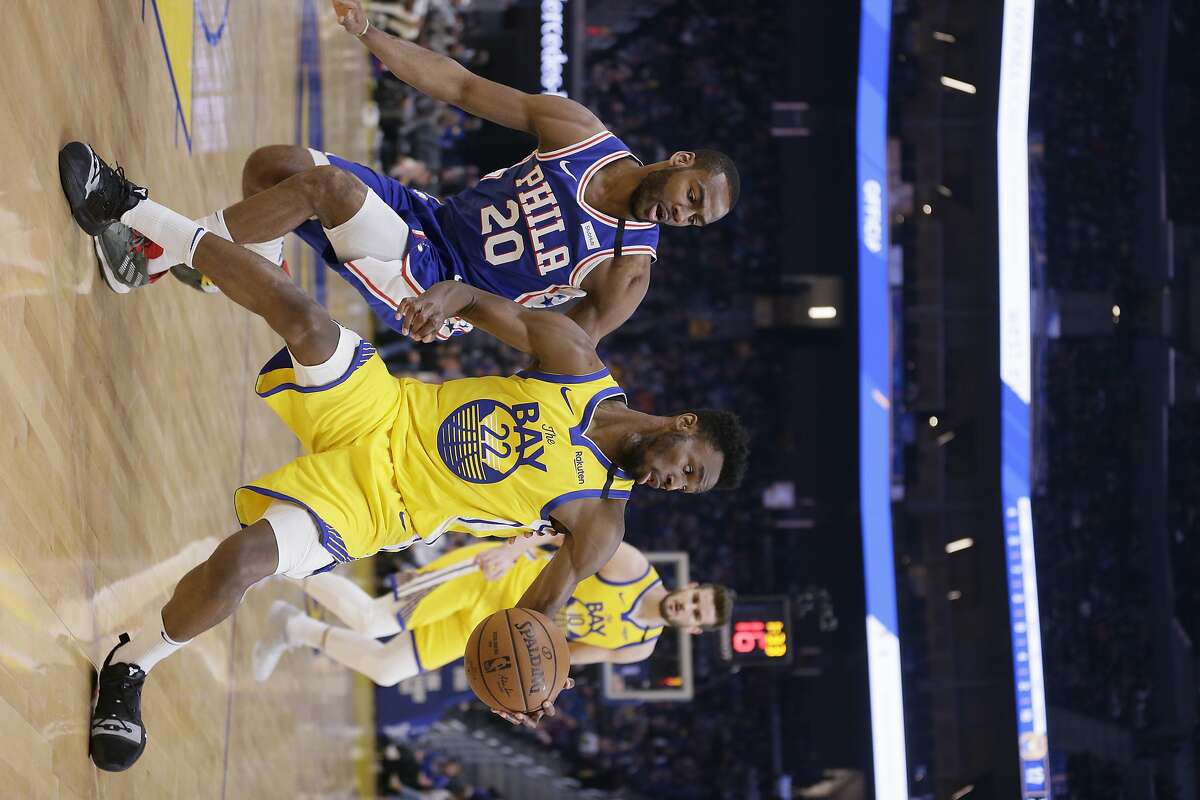 Golden State Warriors guard Andrew Wiggins (22) stops his speed and turns against Philadelphia 76ers guard Alec Burks (20) in an NBA game at Chase Center on Saturday, March 7, 2020, in San Francisco, Calif.