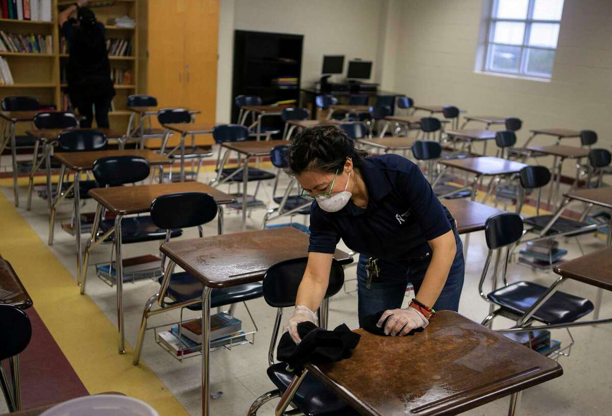 Mary Erazo cleans desks as a custodial crew works to clean classrooms of Dolph Briscoe Middle School in San Antonio, Texas, March 9, 2020. Northside ISD Superintendent Brian Woods sent a letter to parents about coronavirus and Spring Break informing parents that while the students are gone, extra cleaning will be done in classrooms.