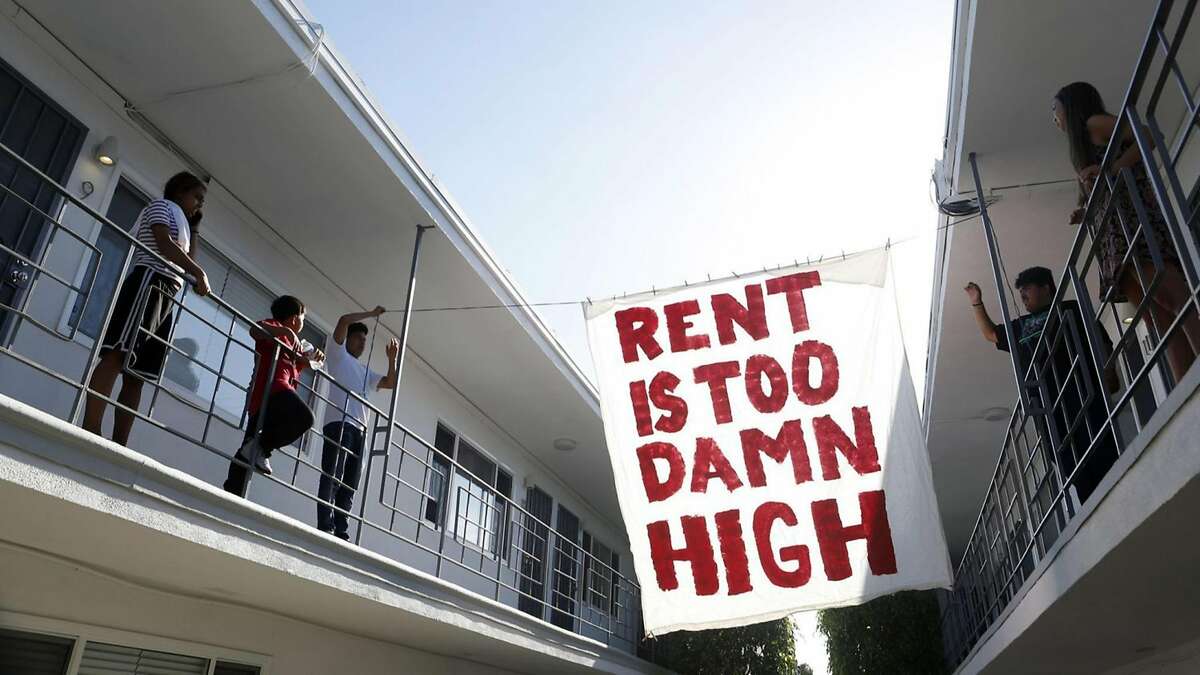 Organizers with Housing Long Beach, a local advocacy group pushing for rent control and eviction protections, hangs up a sign in the courtyard of an apartment complex on Cedar Avenue during a movie night they helped put on with tenants on June 15, 2018 in Long Beach, Calif. (Katie Falkenberg/Los Angeles Times/TNS)