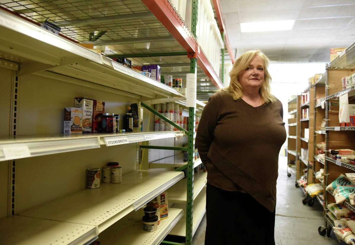 Executive Director Kate Lombardo chats beside a row of empty shelves at the Food Bank of Lower Farifield County in Stamford, Conn. Monday, March 9, 2020. Since the coronavirus outbreak, the food bank has experienced a shortage of food, particularly pasta, cereal and nonperishable canned goods.