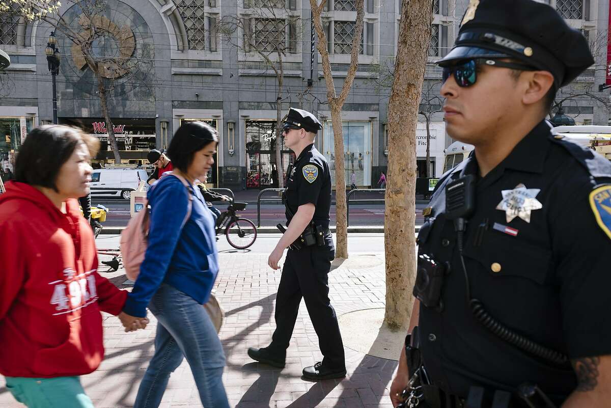 San Francisco Police Officers Cory McDowell, left, and Nick Parkin walk their beat on Market Street in San Francisco, California, on Wednesday, March 4, 2020.