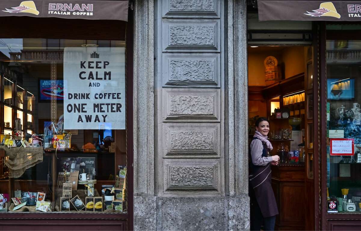 A waitress looks on by a sign advising clients to keep distance on a cafe's window on March 10, 2020 in downtown Milan. - Italy imposed unprecedented national restrictions on its 60 million people on March 10, 2020 to control the deadly coronavirus, as China signalled major progress in its own battle against the global epidemic. (Photo by MIGUEL MEDINA / AFP) (Photo by MIGUEL MEDINA/AFP via Getty Images)