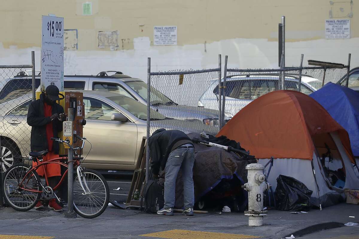 People stand in front of tents on a sidewalk in San Francisco, Tuesday, Feb. 18, 2020. (AP Photo/Jeff Chiu)