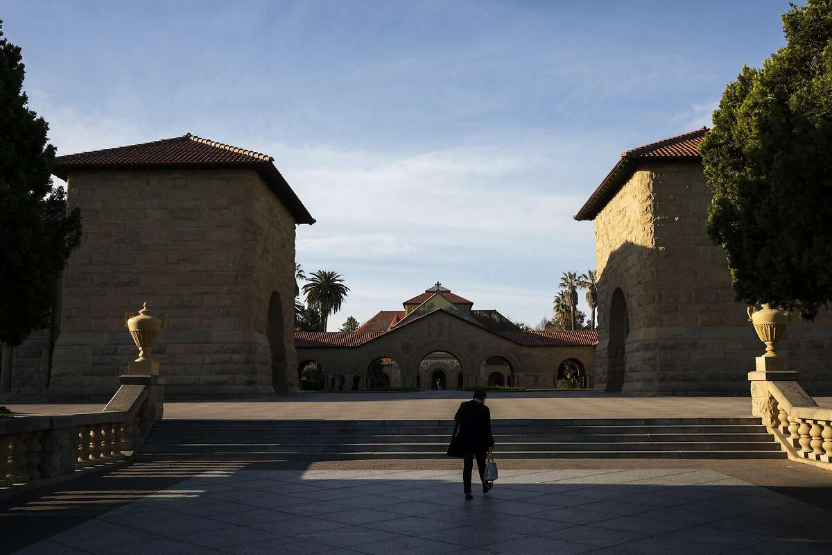 FILE - A person walks towards the main quad during a quiet morning at Stanford University on March 9, 2020 in Stanford, California. The school announced that an undergraduate student has tested positively for coronavirus.