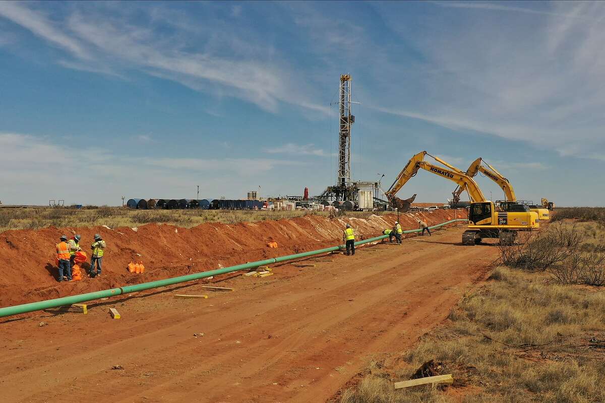 A pipeline is laid out near a drilling rig photographed Feb. 28, 2020 near Loving, New Mexico, in the Permian Basin.