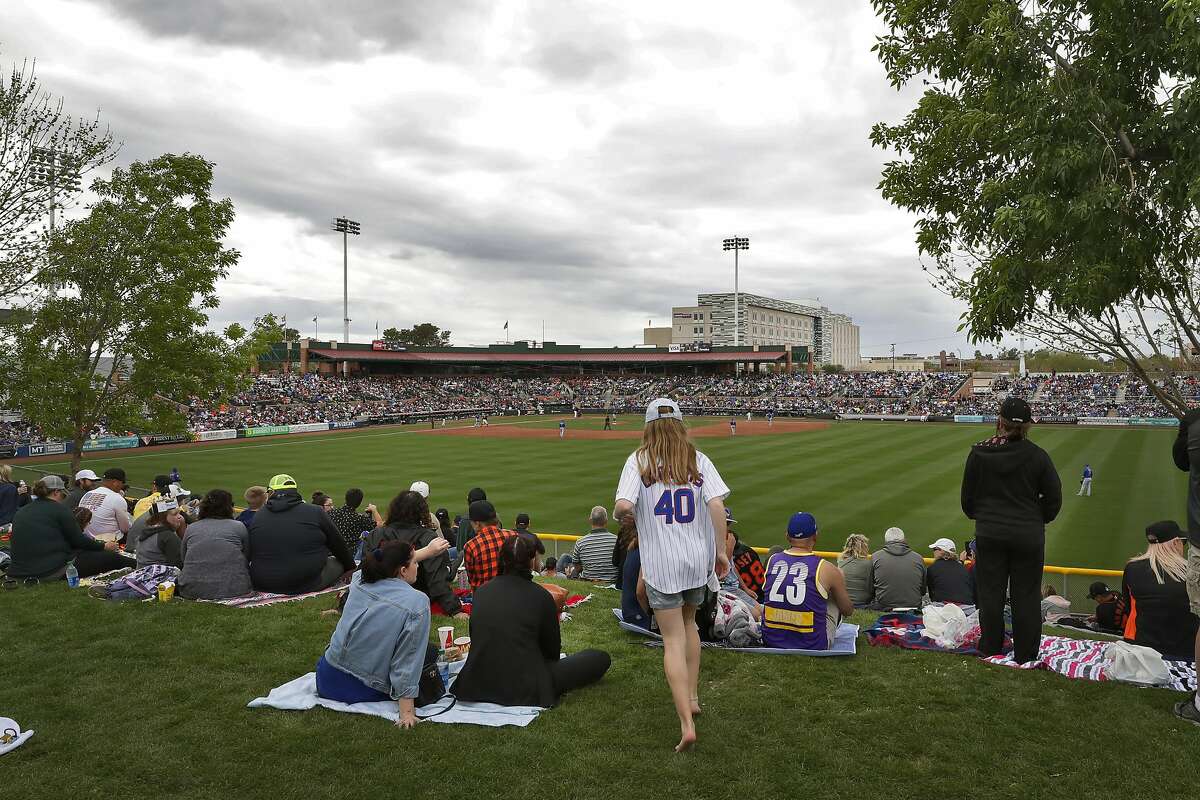 San Francisco Giants and Chicago Cubs fans watch from the center field lawn the third inning of a spring training baseball game Tuesday, March 10, 2020, in Scottsdale, Ariz. (AP Photo/Matt York)