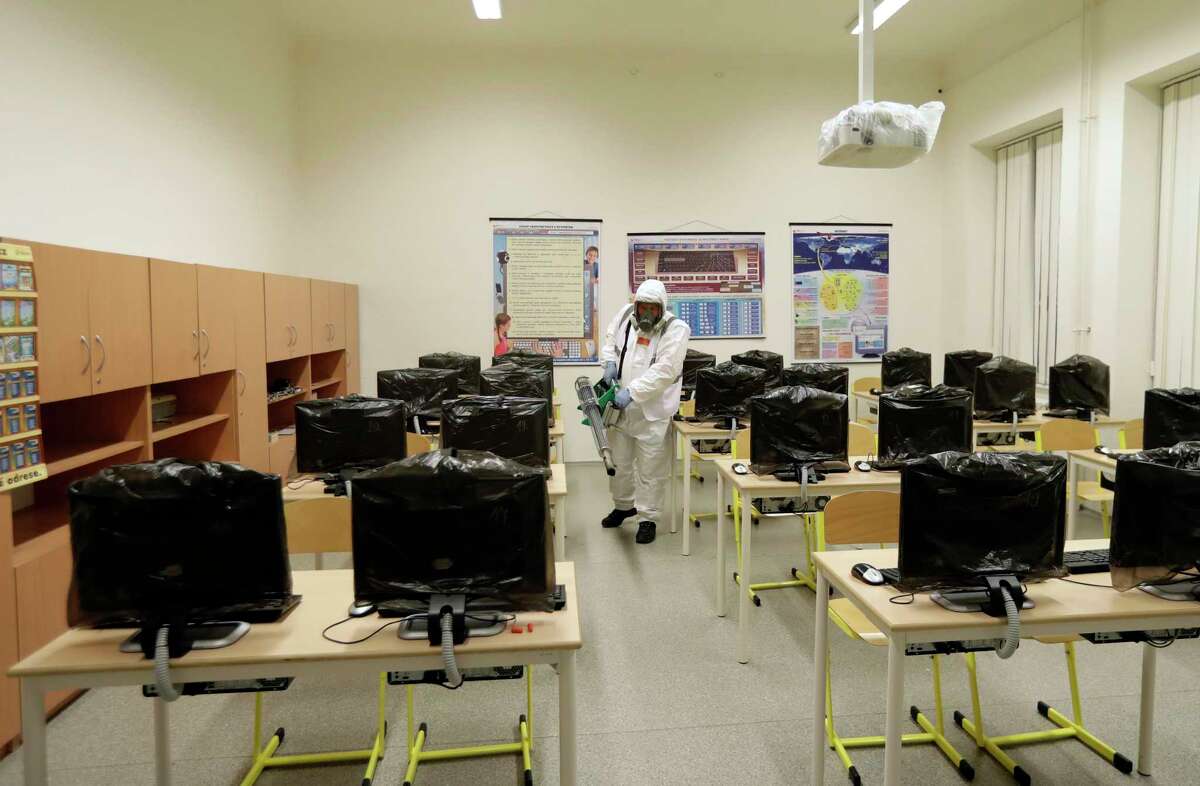 A worker disinfects a classroom at a closed school in Prague, Czech Republic, Tuesday, March 10, 2020. The Czech Republic is banning all public events with more than 100 people and is closing schools in response to the new coronavirus outbreak in Europe. For most people, the new coronavirus causes only mild or moderate symptoms, such as fever and cough. For some, especially older adults and people with existing health problems, it can cause more severe illness, including pneumonia. (AP Photo/Petr David Josek)