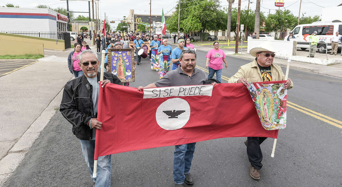 Participants in the Cesar Chavez March for Justice hold up banners depicting the United Farm Workers flag on Saturday afternoon as the procession proceeds down San Bernardo Avenue.
