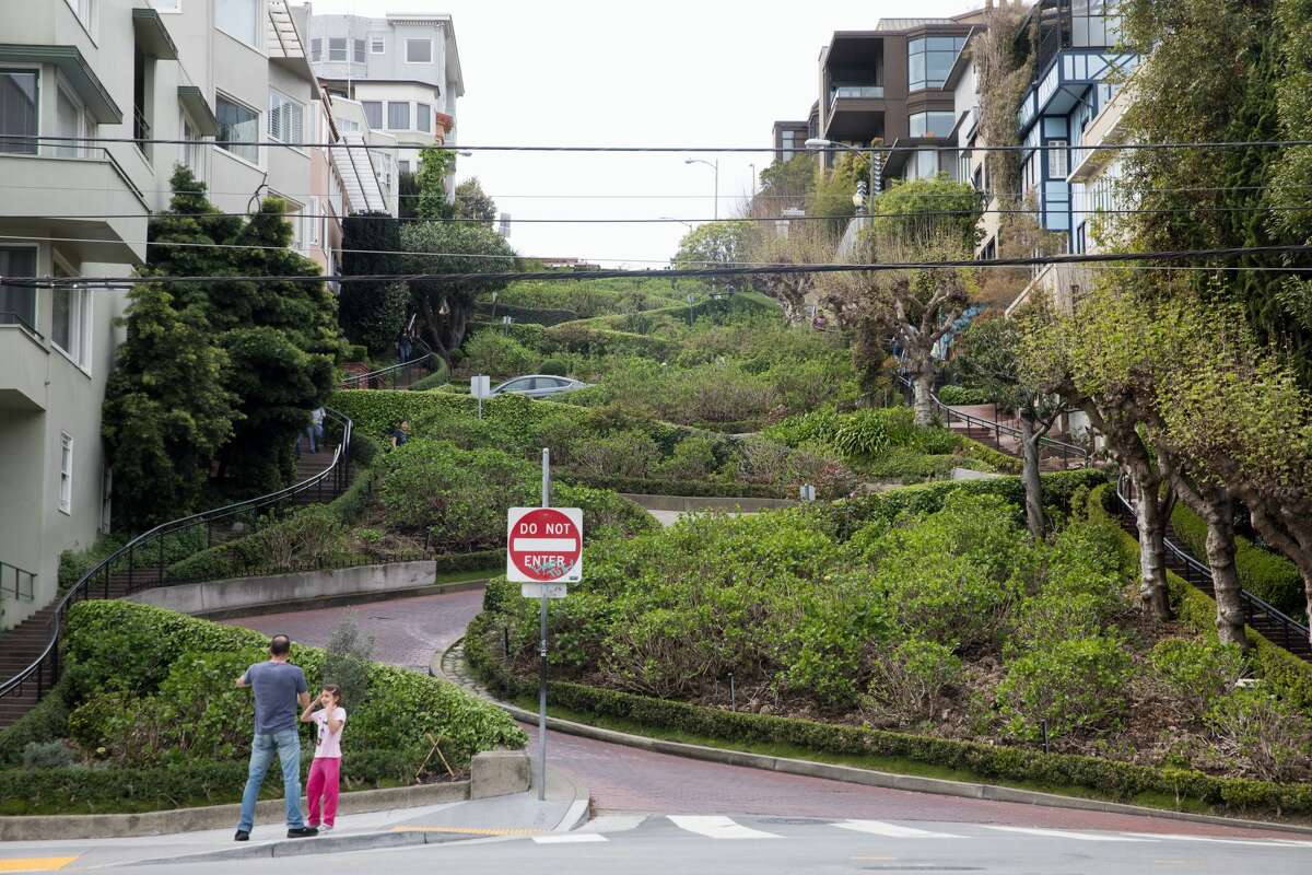 A family poses for a photo in front of a quiet Lombard Street in San Francisco, Calif. on March 10, 2020. Tourist numbers are down in the city because of coronavirus concerns and the cancelation of tours from Asian and European visitors to San Francisco.
