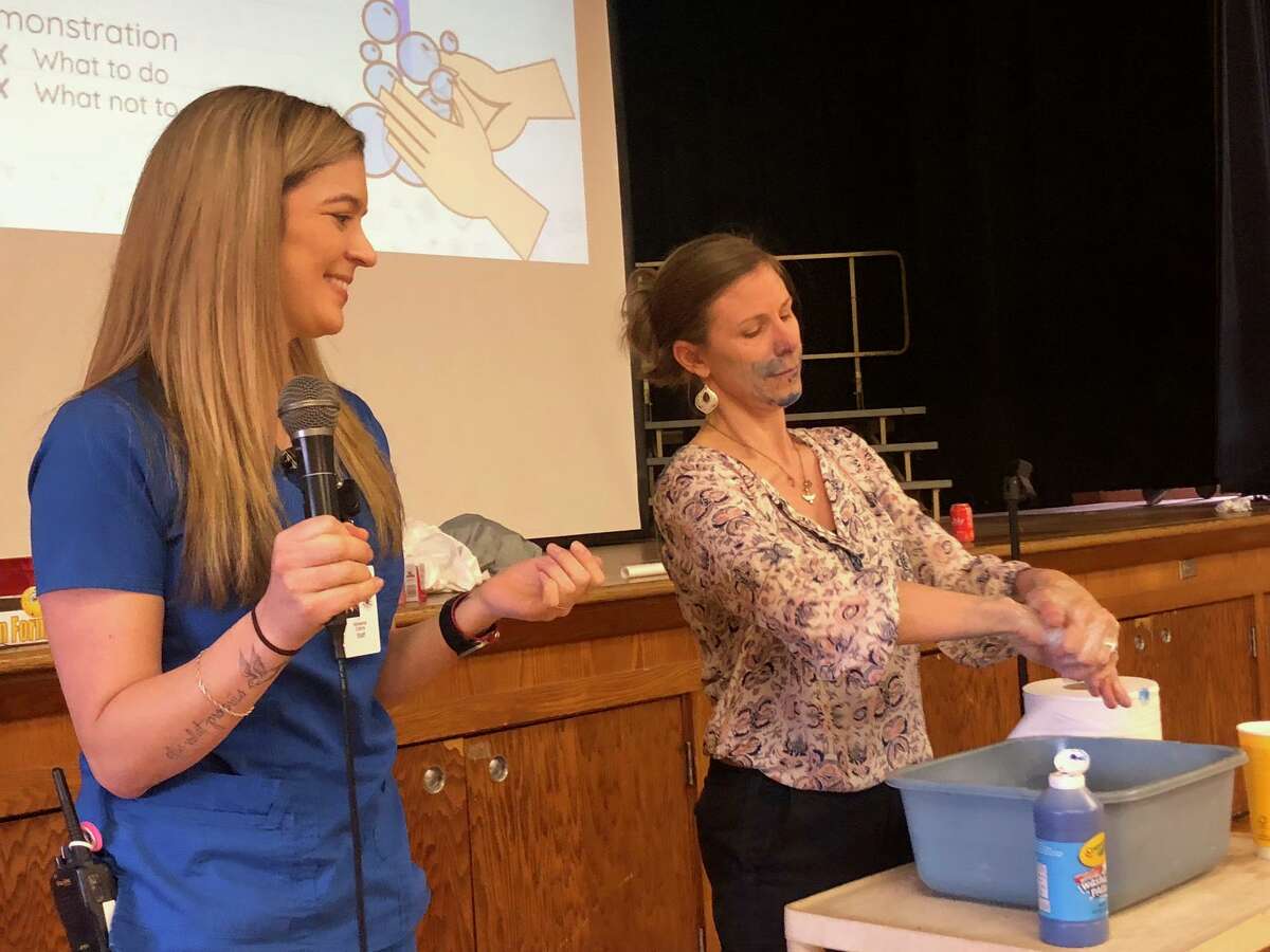 Booth Hill School physical education teacher Nicole Swercewski, right, demonstrates how to best wash hands as school nurse supervisor Adrianna Collins talks to students at the school's assembly Wednesday, March 11.