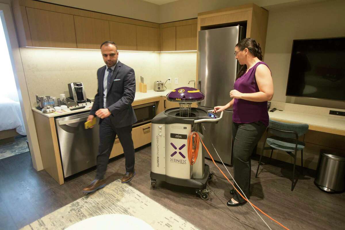 Archit Sanghvi, vice president of operations for Houston-based Pearl Hospitality, owner and manager of The Westin Houston Medical Center and Dr. Sarah Simmons, senior director of science for Xenex Disinfection Services demonstrates one of the two germ-fighting cleaning robots being used at The Westin Houston Medical Center to sanitize and disinfect guest rooms and common areas against the threat of coronavirus Wednesday, March 11, 2020, in Houston.