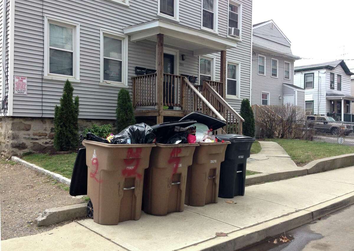 Overflowing garbage cans stand on the curb along Henry Street in Stamford, Conn. on Monday, March 21, 2016. Some neighbors claim that there has been a recent problem with rats, mice, raccoons and skunks the last couple of months because garbage pickup recently began coming only half as frequently as before.