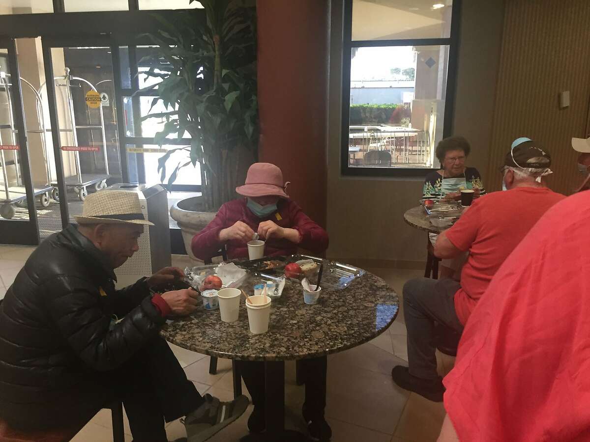 People eat with no masks in common areas at the quarantine site on Travis Air Force Base. A group of Grand Princess passengers are under 14-day quarantine there.