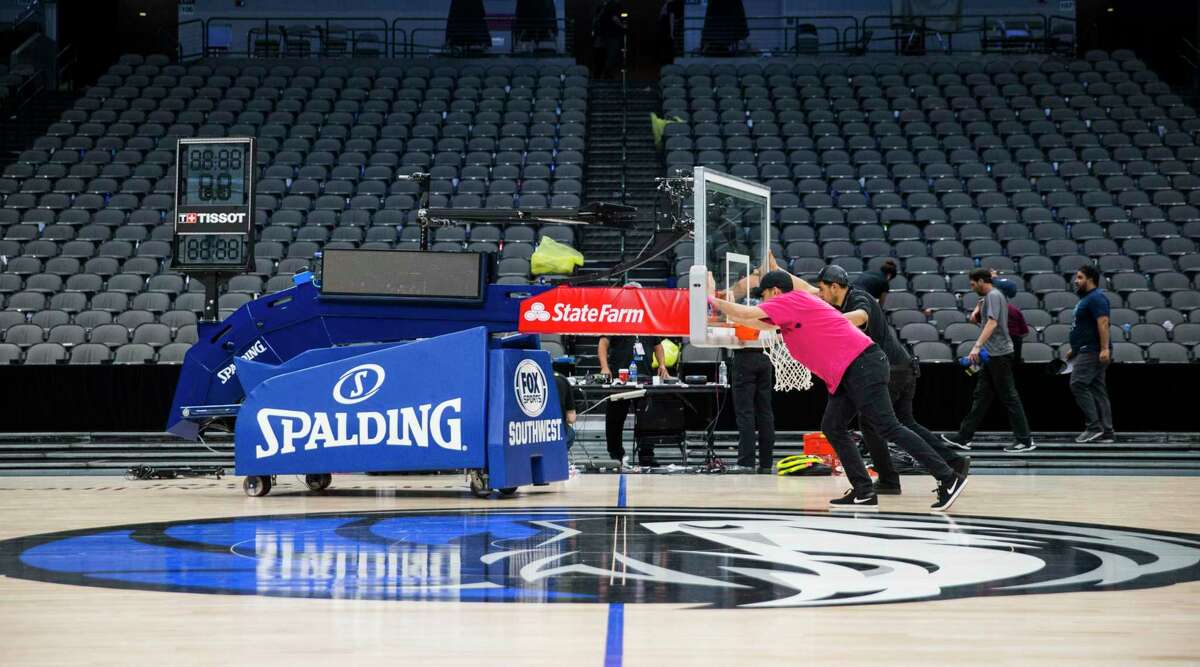Crews remove a basketball hoop from the court after the Dallas Mavericks defeated the Denver Nuggets in one of the last games before the league suspended the season.