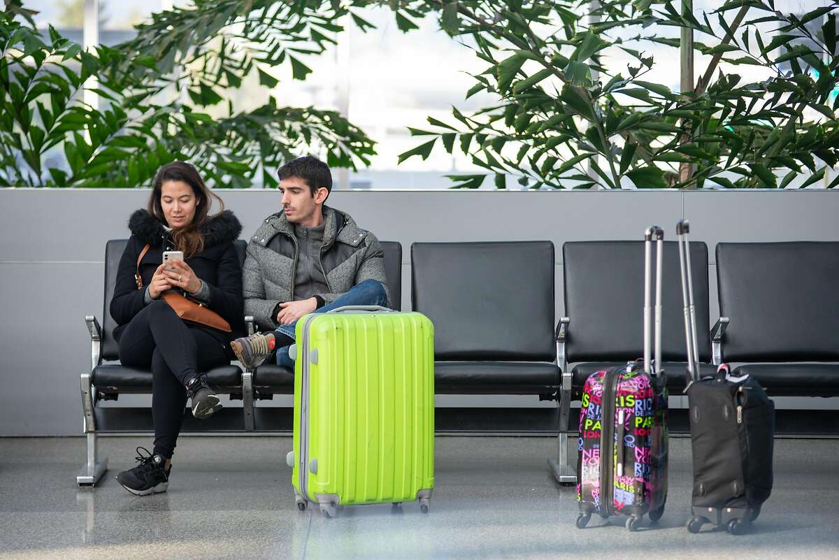 Honeymooners, Nhuvi Nguyen and Nicolas Weglinkski, try to get on a flight back to France one day into their vacation the day after President Trump banned on all air travel from Europe for 30 days International Terminal at San Francisco International Airport on March 12, 2020 in San Francisco, Calif. They are concerned French President Macron with announce a travel ban in France later this evening and are trying to get home before a lockdown in France.