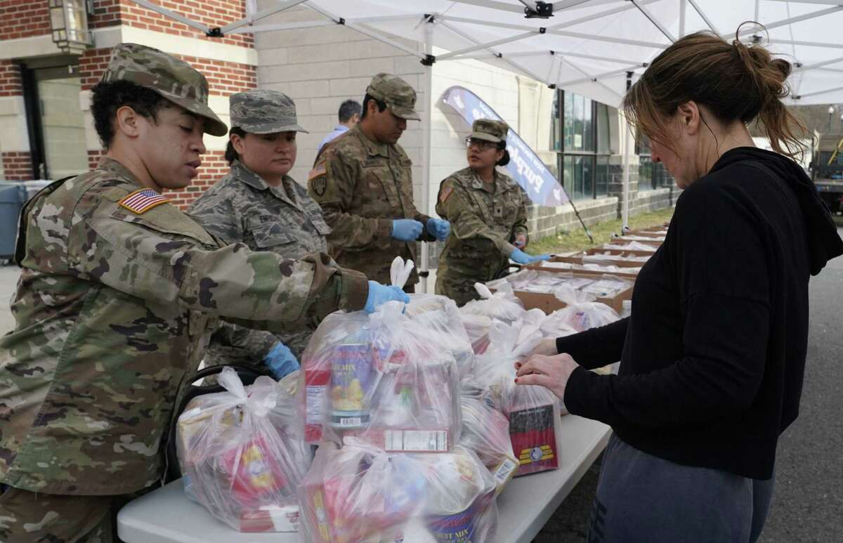 National Guard troops give food to residents of New Rochelle, New York at New Rochelle High School March 12, 2020. - The National Guard will help clean surfaces and deliver food in the one-mile radius containment area around a point near a synagogue connected to some existing cases of what appears to be the nations biggest cluster of cases of the coronavirus, COVID-19.US President Donald Trump announced a shock 30-day ban on travel from mainland Europe over the coronavirus pandemic that has sparked unprecedented lockdowns, widespread panic and another financial market meltdown March 12, 2020. The announcement came as China, where the outbreak that first emerged in December, showed a dramatic drop in new cases and claimed "the peak" of the epidemic had passed.