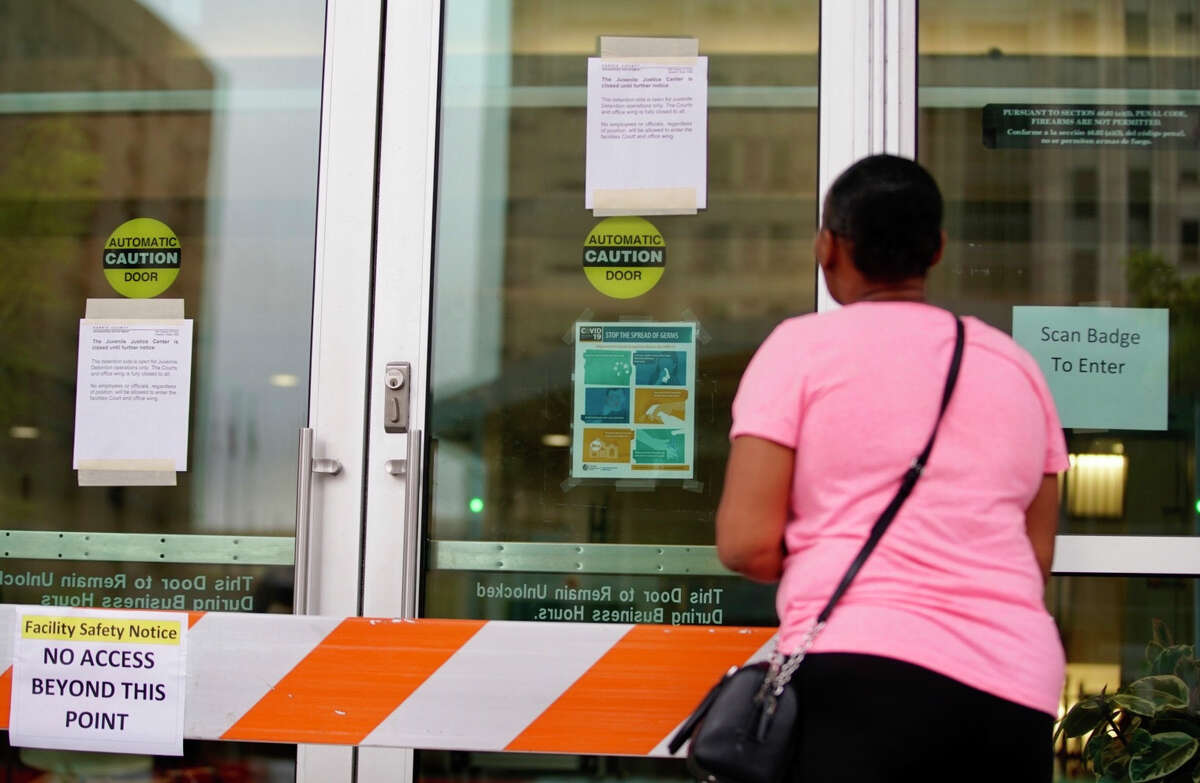 Aurelia Ray, of Houston, looks at the locked doors that are blocked and signs posted on the doors of the Harris County Juvenile Justice Center Friday, March 13, 2020, in downtown Houston. Ray has a daughter currently locked in the building who she is trying to get an inhaler to.