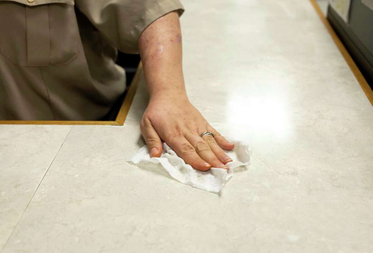 A security guard at the Lee G. Allworth building in Conroe wipes the counter with a disinfectant wipe.