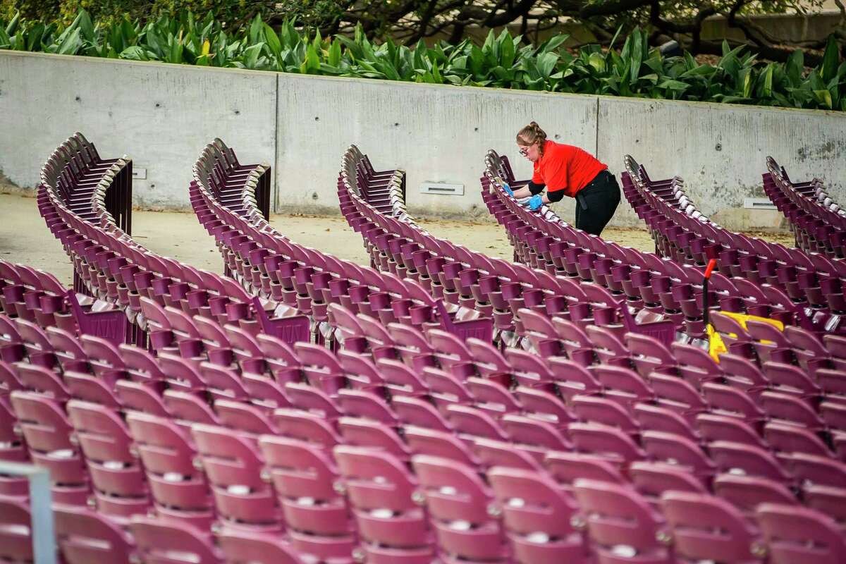 A worker cleans the seats at Miller Outdoor Theater, Friday, March 13, 2020, at Hermann Park in Houston.