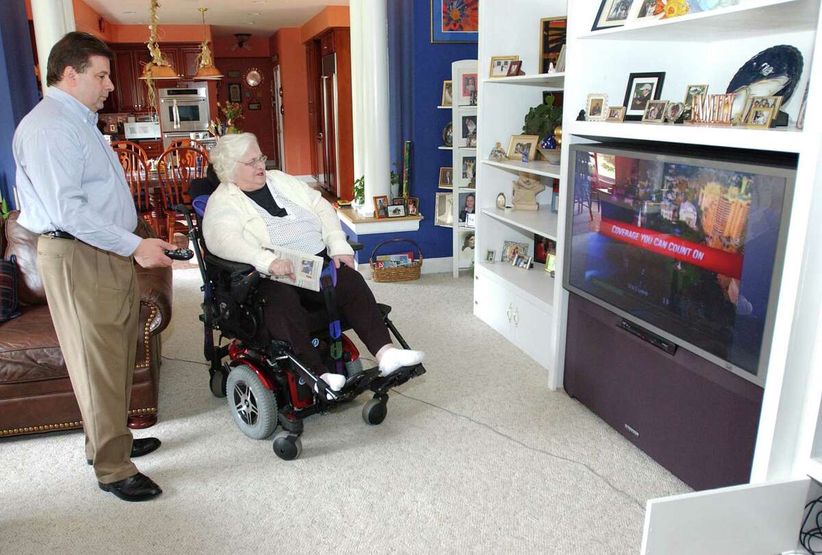 HVIZDAK ph0456a #0516 Southbury, Connecticut-6/16/06: Joe Stango, left, with his mother Dora Stango, 83, who is afflicted with Spinal Stenosis, watching TV together in his Southbury home. Dora is confined to a wheelchair and needs around-the-clock care. Stango put her in a nursing home three years ago and since then has waged a one-man crusade to get the state and federal Medicaid laws changed to allow payment to people to care for elderly relatives at home, rather than just nursing homes. Connecticut will apply to be one of 10- states selected for a new pilot program by the Bush administration called "Money Follows the Person", designed to allow federal Medicaid contributions to go toward in-home care.