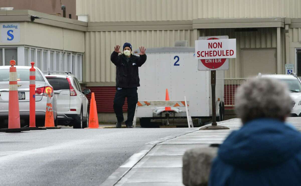 A hospital employee is seen directing cars as they drive up next to a tent set up in the rear parking lot of Albany Medical Center as a place to test people for COVID-19, also called the novel coronavirus on Friday, March 13, 2020 in Albany, N.Y. People in their cars are assessed according to their symptoms to whether they get tested for the virus. (Lori Van Buren/Times Union)