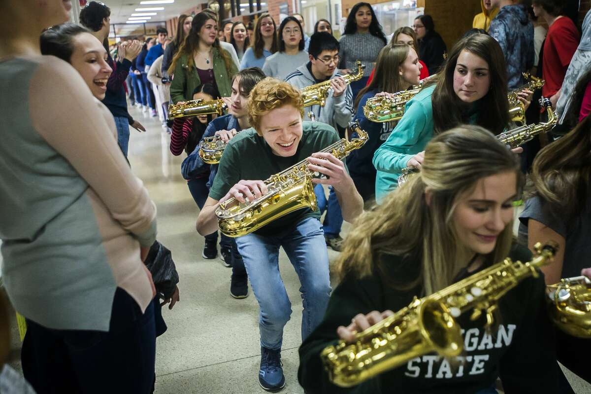 Dow High student TJ Neuenfeldt, center, crouches down as he dances through the hallway with the marching band as they perform during a pep rally Thursday, March 12, 2020 in support of Dow teams that were supposed to move forward in their prospective state tournaments. All MHSAA sporting events have been postponed as a preventative measure to curb the spread of COVID-19. (Katy Kildee/kkildee@mdn.net)