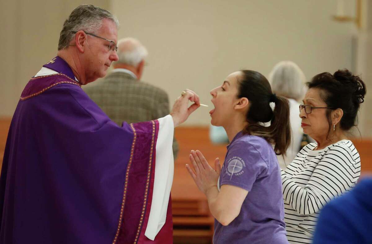 Fr. Lawrence W. Jozwiak gives the faithful the Eucharist, but not Precious Blood, due to the COVID-19 outbreak during the midday Mass in the Co-Cathedral of the Sacred Heart Friday, March 13, 2020, in Houston.