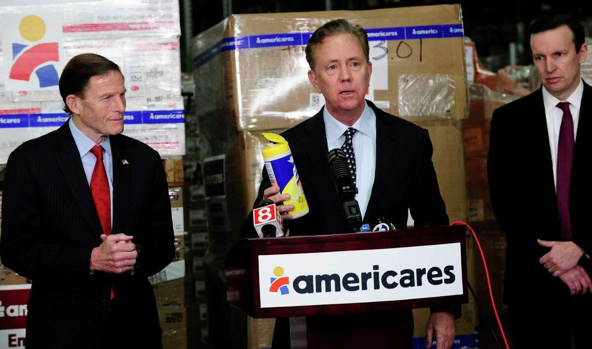 Gov. Ned Lamont and U.S. Senators Richard Blumenthal and Christopher Murphy visited Americares' headquarters and global distribution center at 88 Hamilton Ave., in Stamford, Conn., to receive an update on the health-focused relief and development organization's response to the COVID-19 pandemic on March 13, 2020. Lamont holds a container of cleaning wipes as he speaks with the media.