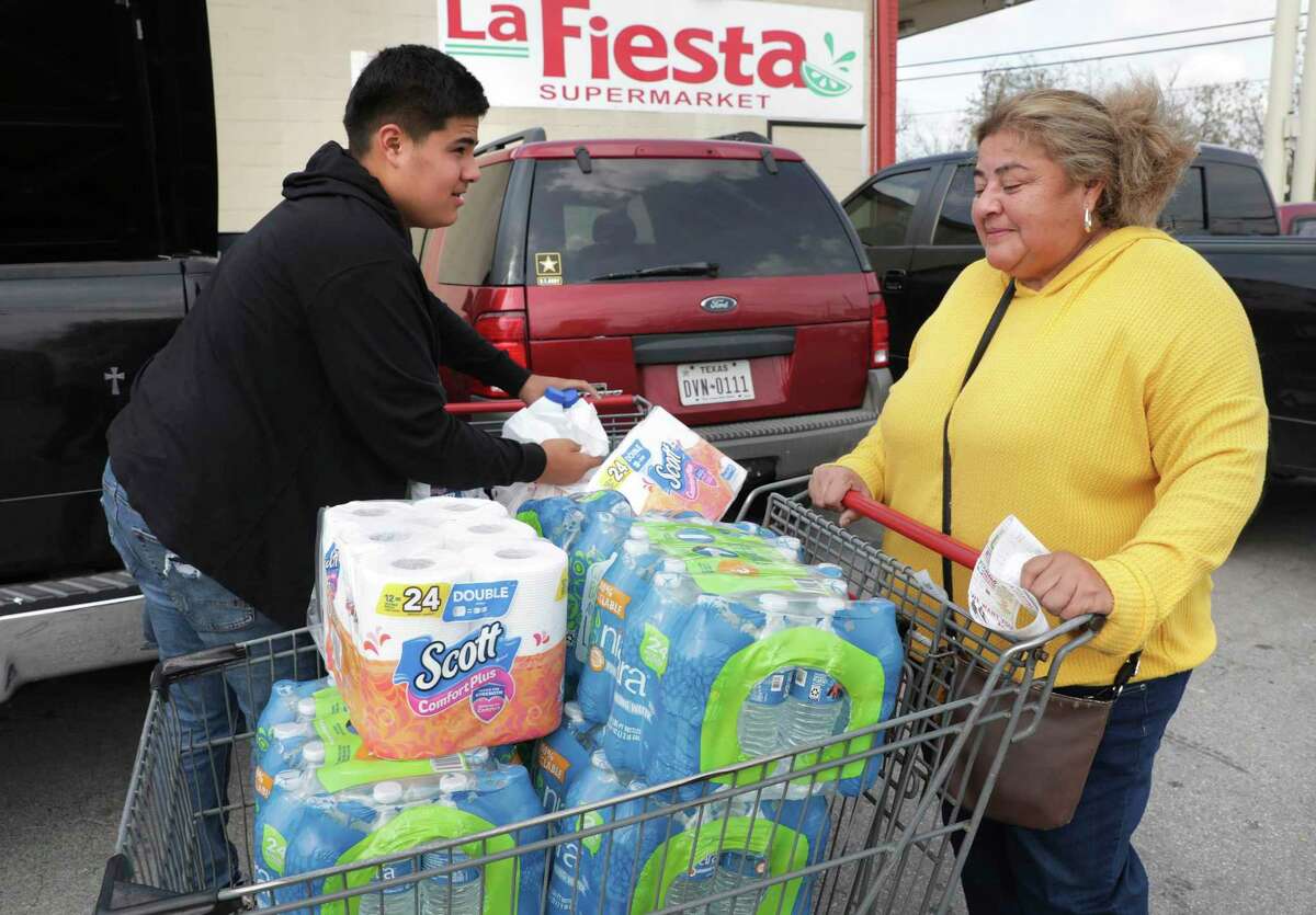 Anna Saenz, right, gets help from son Gabriel Thomas while loading groceries including water and toilet paper Friday, March 13, 2020.