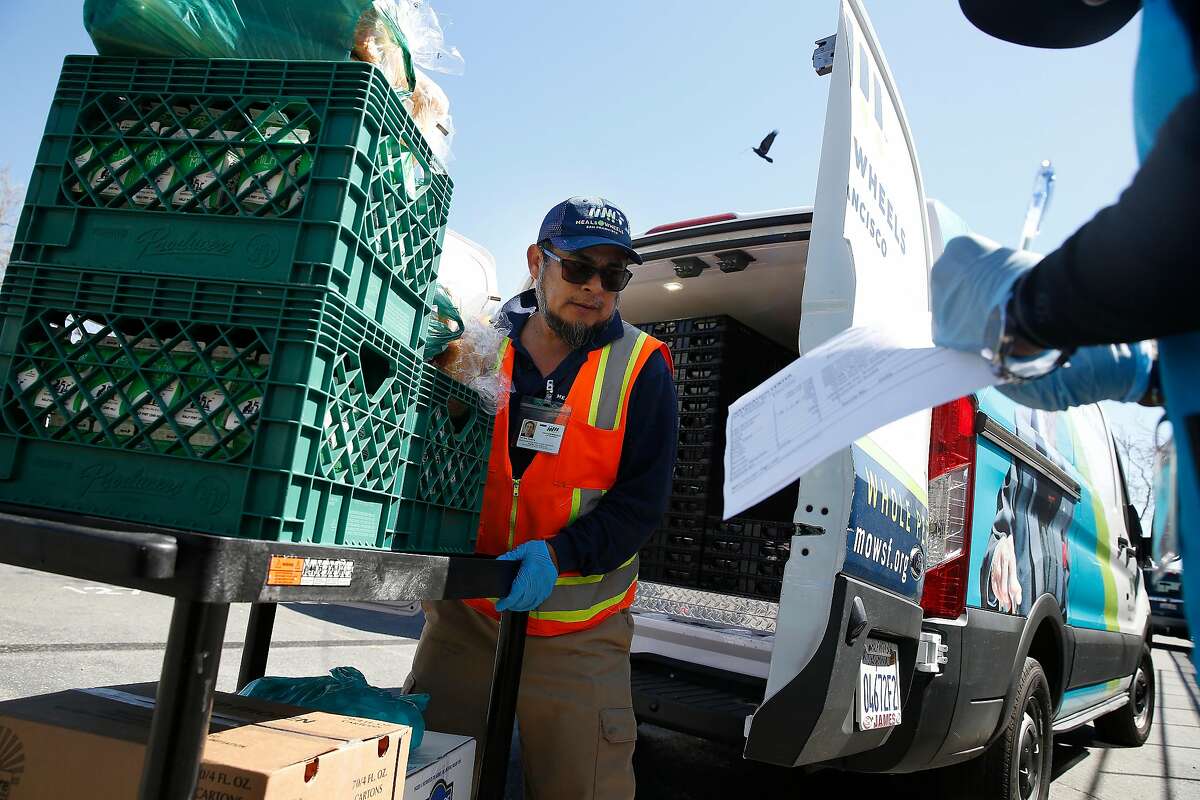 Santos Cetina (l to r), Meals on Wheels driver, makes a Meals on Wheels delivery to the Embarcadero Navigation Center as Michael Tillman, operation ambassador Embarcadero Navigation Center signs for the delivery on Thursday, March 12, 2020 in San Francisco, Calif.