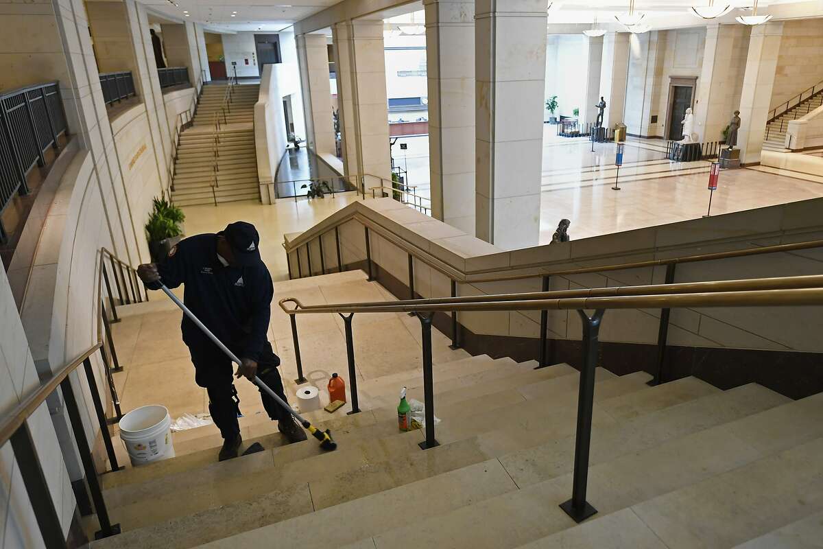 Carroll Rodgers of Washington, cleans steps in the Capitol Visitor Center on Capitol Hill in Washington, Friday, March 13, 2020. Because the Capitol Visitor Center is closed, employees are able to do their regular cleaning later in the day instead of only in the very early ours of the days before tourists come through. (AP Photo/Susan Walsh)